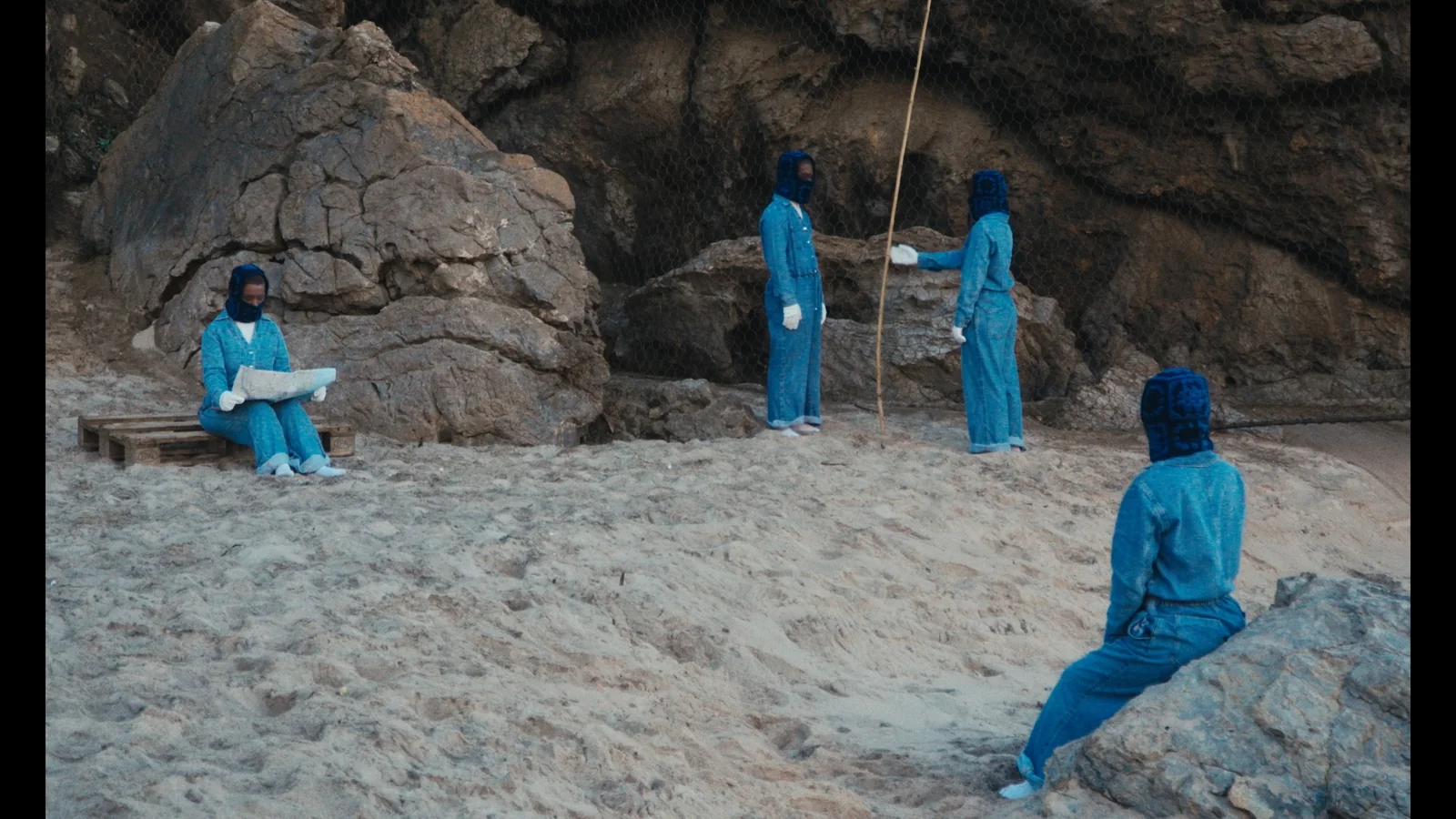Figuras de fato azul numa praia entre rochedos